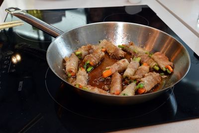 High angle view of steak rolls being fried in pan on stove