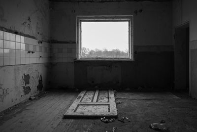 An old room with a door on the floor and a broken window