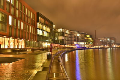 Illuminated city by river at night