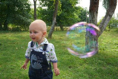 Bubble flying by boy standing on grassy field at park