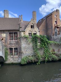 Old building by canal against sky