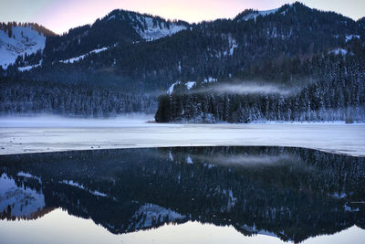 Scenic view of lake by snowcapped mountains during winter