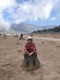 Man sitting on landscape against mountain range