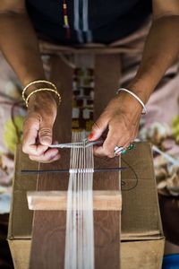 Midsection of woman weaving traditional accessories