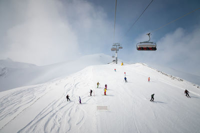 Panorama of the ski resort, slope, people on the lift, skiers and snowboarders on the track with