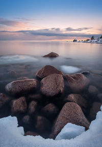 Rocks in sea during sunset