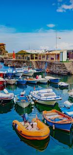 Boats moored at harbor in city against sky