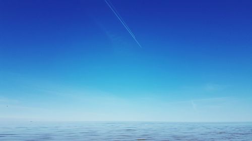 Contrails below calm blue sea