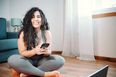 Smiling young woman using phone at home