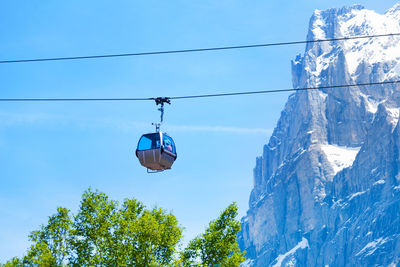 Low angle view of overhead cable car against blue sky