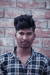 Portrait of young man standing against wall