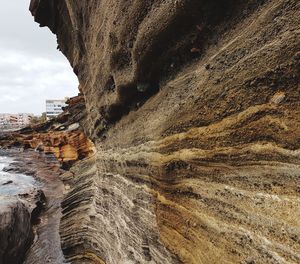 Rock formation on shore against sky