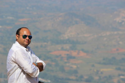 Portrait of man wearing sunglasses against landscape 