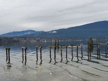 Wooden posts in lake against sky