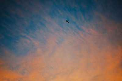 Low angle view of silhouette airplane against sky