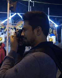 Side view of young man using mobile phone at night