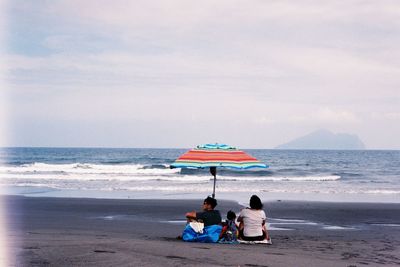 Rear view of people on beach against sky