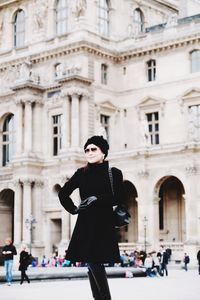 Woman wearing sunglasses while standing against historical building