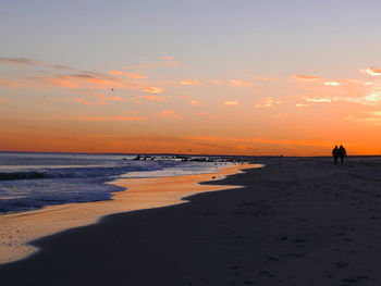 Silhouette person on beach against sky during sunset