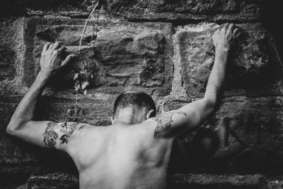 Rear view of shirtless man standing on rock