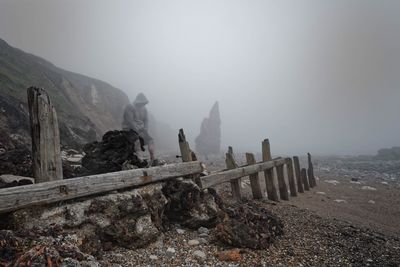 Man sitting on rocks during foggy weather