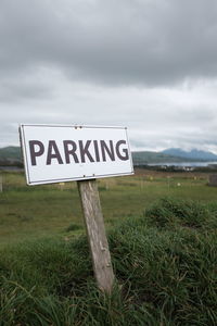 Information sign on field against sky