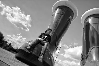 Low angle view of teenage boy sitting on large shoe