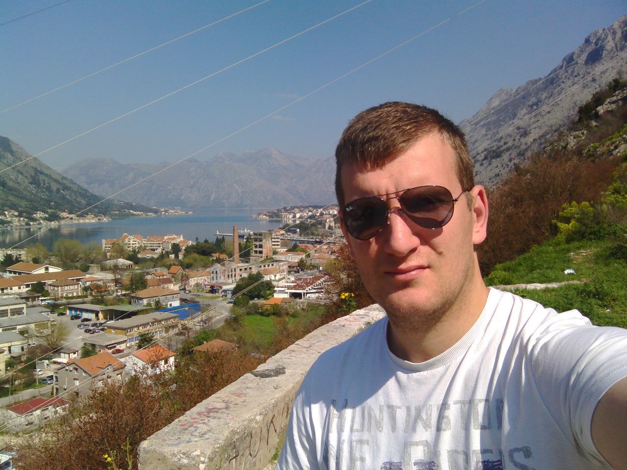 young adult, lifestyles, portrait, building exterior, person, looking at camera, sunglasses, casual clothing, leisure activity, young men, architecture, built structure, mountain, front view, smiling, sky, headshot