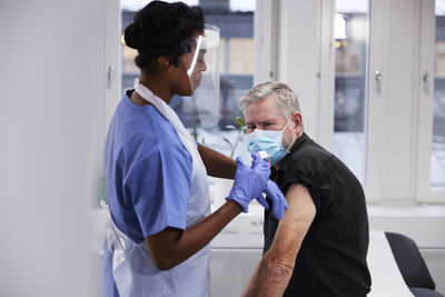 Female doctor vaccinating senior patient