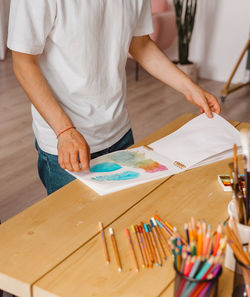 Attractive young creative man.sketchbook.wooden table. concept diy. real art maker in action