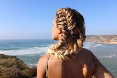 Rear view of woman looking at sea against clear sky