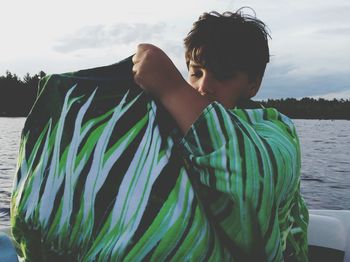 Boy holding scarf while sitting in boat on lake