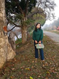 Full length of young woman standing in forest