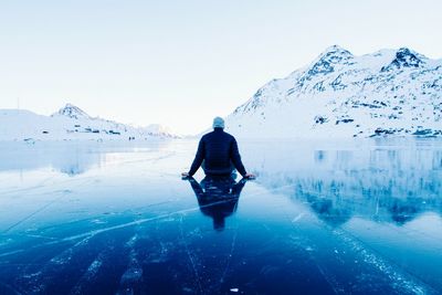 Rear view of man walking on snowcapped mountain