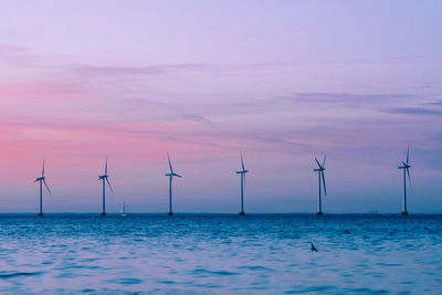 Scenic view of wind turbines against sky during sunset