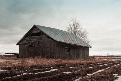 Old wooden house on field against sky