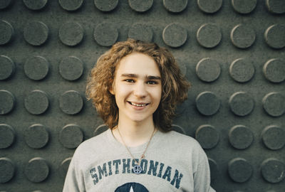 Portrait of smiling young man standing against wall