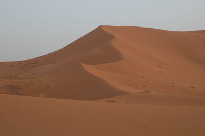 Sand dunes in desert against clear sky