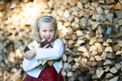 Portrait of smiling girl standing by wood