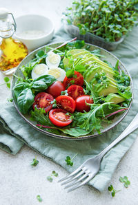 Fresh summer salad with arugula, red cherry tomatoes, basil, eggs and avocado. vegan food. 