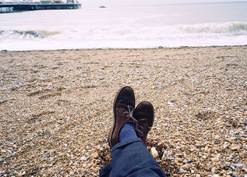 Low section of man relaxing at beach