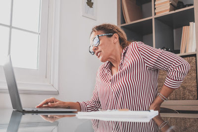 Side view of young man using laptop while sitting at home