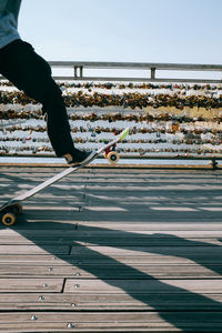 Low section of man skate boarding in paris city on a bridge against sky
