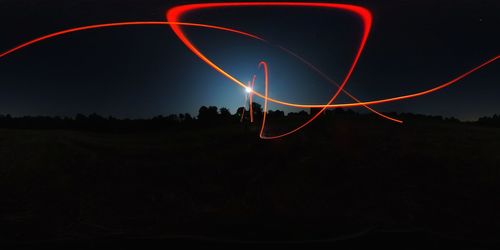 Low angle view of light trails on field against sky at night