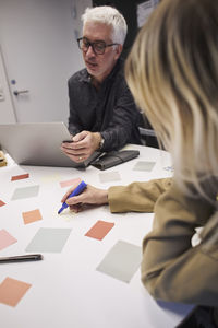 Business people using sticky notes and laptop in office