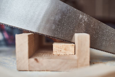 Close-up of hand saw on wood