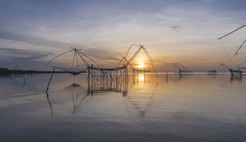 Fishing net by sea against sky during sunset