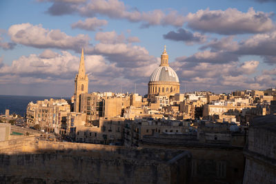 Buildings in city against cloudy sky