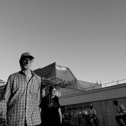 Low angle view of people standing on bridge against clear sky