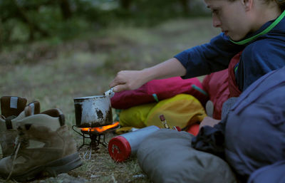 Woman preparing food on camping stove during sunset